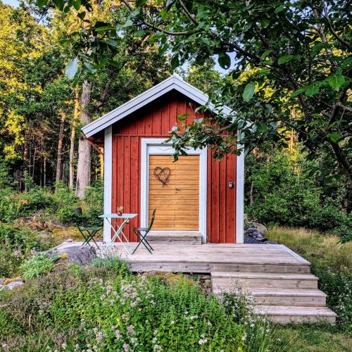a red shed with a door with a wooden ramp at Mysig stuga, Oskarshamn in Oskarshamn