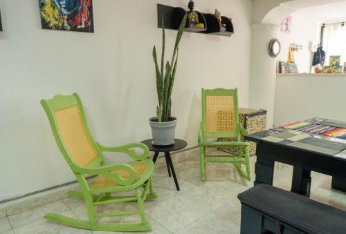two green chairs and a table with a potted plant at Hostal Casa Yare in Rodadero