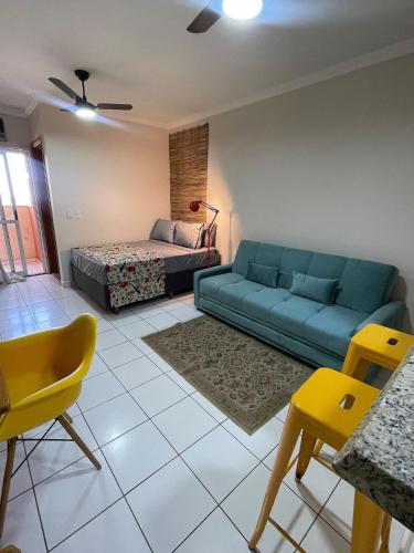 a living room with a blue couch and a bed at Edifício Belluno in Ribeirão Preto