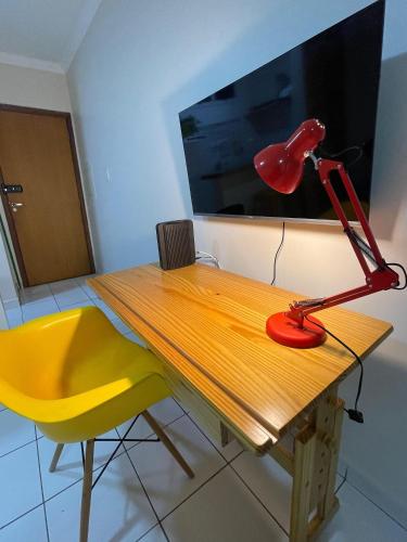 a red lamp sitting on a wooden table with a yellow chair at Edifício Belluno in Ribeirão Preto