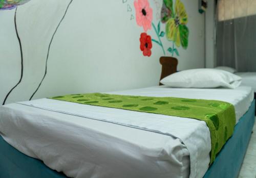 a bed with a green blanket on top of it at Hostal Casa Yare in Rodadero
