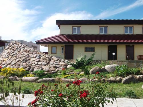 a yellow house with a pile of rocks and flowers at AgroecoUsadba U Druzey in Gorodnya
