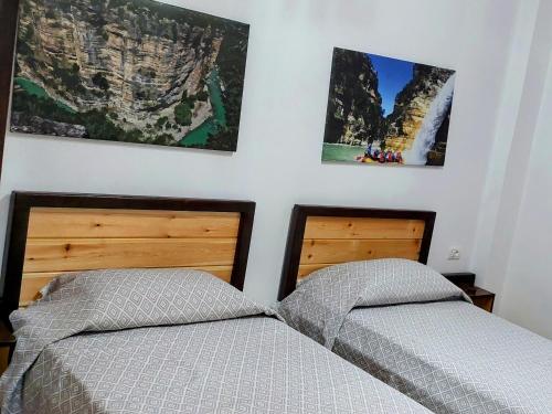 two beds in a bedroom with two posters on the wall at Sweet Home Aria in Çorovodë