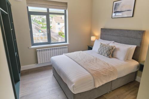 a bedroom with a large bed with a window at Riverside Dingle - Luxury Apt 4 in Dingle