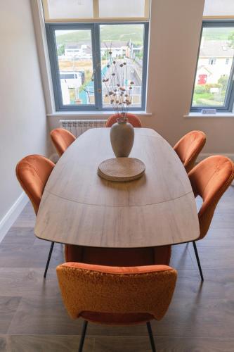 a dining room table with chairs and a vase on top at Riverside Dingle - Luxury Apt 4 in Dingle