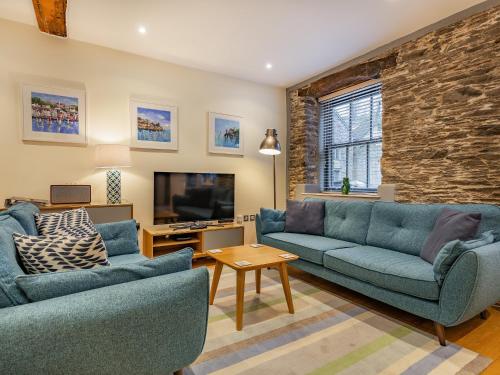 Una sala de estar con dos sofás azules y un televisor. en The Pottery, en Dartmouth