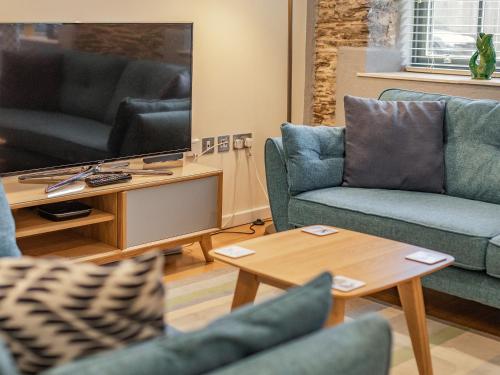 Una sala de estar con sofás azules y una mesa. en The Pottery, en Dartmouth