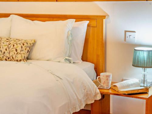 a bedroom with a bed and a table with a lamp and a book at 1 Bed in Kidwelly 43406 in Kidwelly