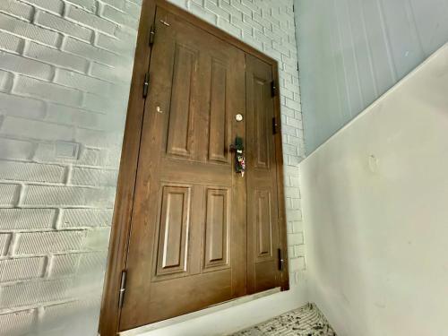 a wooden door in a white brick wall at Komolon in Tashkent