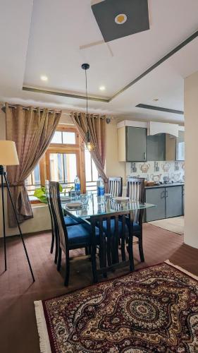 a dining room with a table and chairs and a kitchen at Soma Hotels Skardu in Skardu