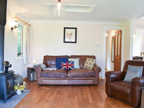 a living room with a brown couch and a chair at Drumble Lodge in Astbury