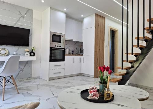 una cocina con armarios blancos y una mesa con flores en Oaza mira 2, en Jajce