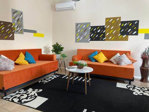 a living room with two orange couches and a table at Villa Oni in Tirana
