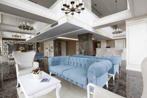 a living room with a blue couch and white chairs at Hanzade Park Hotel in Trabzon
