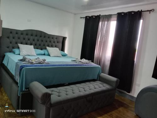 a bedroom with a bed and a couch and a window at Casa vistas de puerto mantica in Poneloya