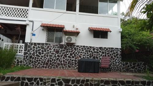 a white building with a stone wall next to a patio at Casa vistas de puerto mantica in Poneloya