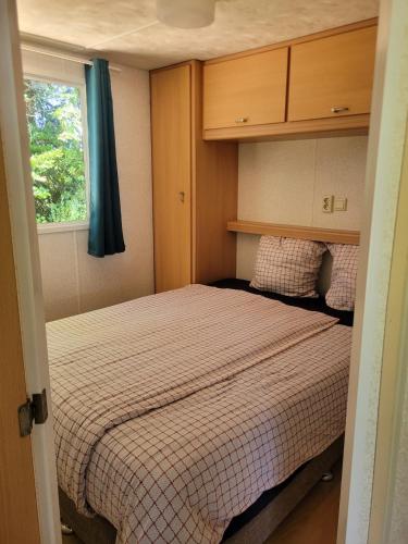 une petite chambre avec un lit et une fenêtre dans l'établissement Stacaravan 4 persoons - Camping Le Soustran, à Neuvic