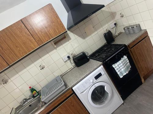 a kitchen with a stove and a washing machine at 2 Luxury Interconnecting Twin Rooms-Shared Space in Basildon