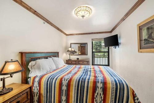 a bedroom with a bed and a lamp and a window at Landmark Vail - Charming Condo for 8 with Resort-style Amenities in Vail