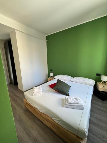 a bedroom with a large white bed with green walls at Ca' Buscion in Stresa