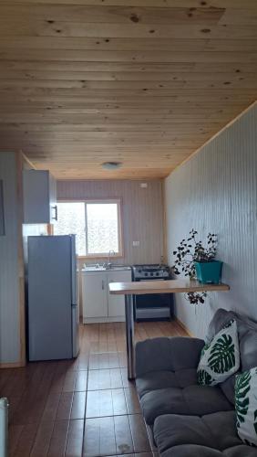 a kitchen with a couch and a table and a refrigerator at Cabaña Aeropuerto el Tepual in Puerto Montt