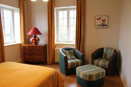 a bedroom with a bed and two chairs and a lamp at Le château de Mesnil 1916 in Mesnil-Martinsart