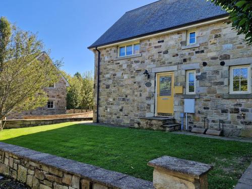 a stone house with a yellow door and a yard at 2 Bed in Nr Beadnell 77990 in Ellingham