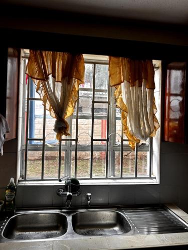 a kitchen window with curtains over a sink at Axis Guest House in Syokimau