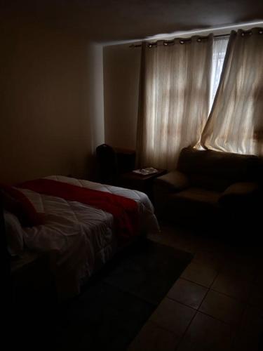 a dark room with a bed and a window at Axis Guest House in Syokimau