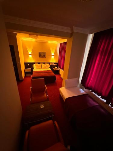 a hotel room with two beds and chairs and red carpet at Minabir Otel in Ankara