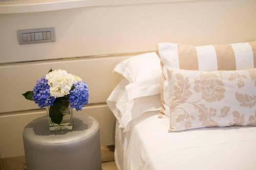 a vase of flowers on a table next to a bed at Hotel Mon Cheri in Riccione
