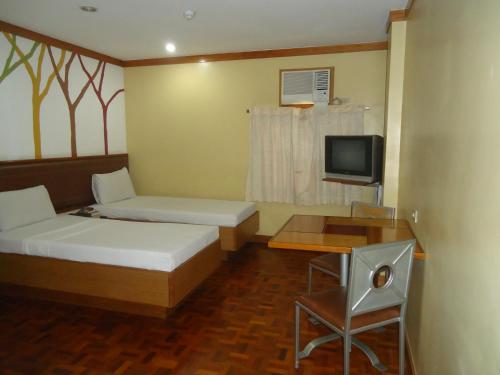 Habitación pequeña con 2 camas y TV. en Park Bed and Breakfast Hotel Pasay en Manila