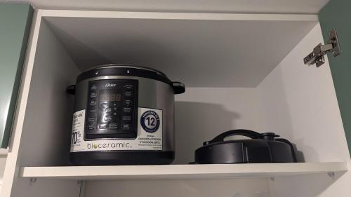 a slow cooker and a pot on a shelf at Elegante y comodo departamento en 1er piso, 3 camas 1 sofa cama in Chiclayo
