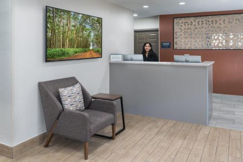 a woman standing at a counter in a waiting room at Candlewood Suites Miami - Doral by IHG in Tamiami
