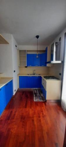 an empty kitchen with blue cabinets and a wooden floor at PM 23 Via Rogge Guest House in Rosà