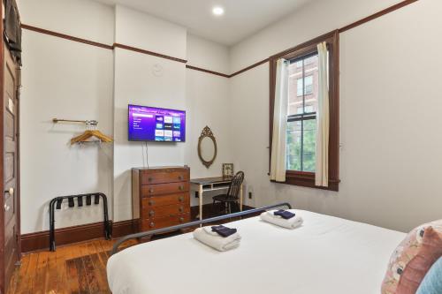 a bedroom with two beds and a desk and a tv at Site 61 Guesthouse in New Orleans