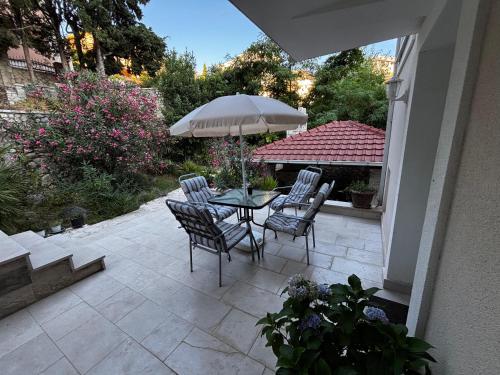 a patio with a table and chairs and an umbrella at Stone Villa Guesthouse in Budva