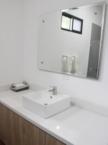 a white bathroom with a sink and a mirror at Hotel El Arca, Jardín Botánico y Restaurante in Santa Bárbaraa