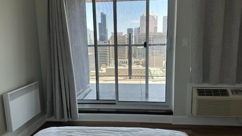 a bedroom with a window with a view of a city at Great view 1BDRM APTR in heart of Montreal DWTN in Montréal