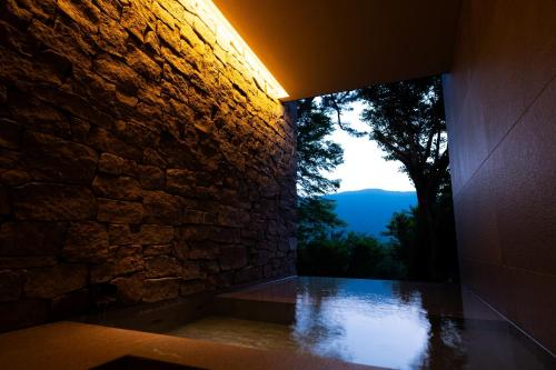 a room with a stone wall and a view of a mountain at Hakone Fontaine Bleau Sengokutei in Hakone