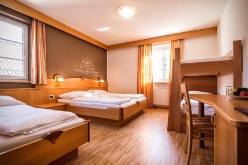 a hotel room with two beds and a desk at Hotel Löwenwirt in Cermes