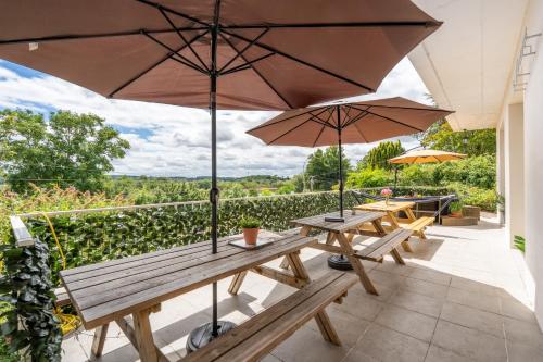 two picnic tables with umbrellas on a patio at Maison SPA 8Chambres Jardin Terrasse Parking in Blois