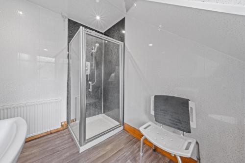 a bathroom with a shower and a chair next to a sink at Struy Guest House - Inverness in Inverness