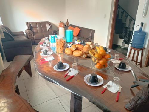 a table with a tray of bread and a bowl of fruit at Hostel do Papai 3 in Lavras