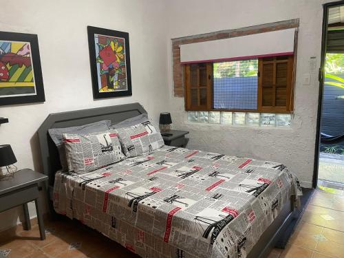 a bedroom with a bed with a comforter and a window at Alemao Cabanas in Camburi