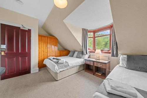 a bedroom with two beds and a window at Struy Guest House - Inverness in Inverness