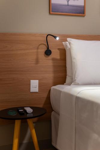 a bedroom with a bed and a table with a lamp at Soft Inn Alagoinhas in Alagoinhas