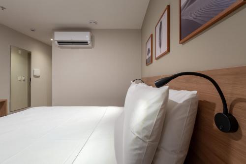 a hotel room with a bed with a pillow on it at Soft Inn Alagoinhas in Alagoinhas