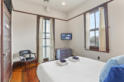 a bedroom with a bed and a chair and a television at Site 61 Guesthouse in New Orleans