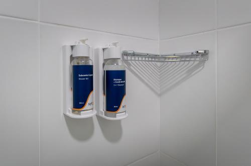 two bottles ofodorizers are on a shelf in a bathroom at Soft Inn Alagoinhas in Alagoinhas